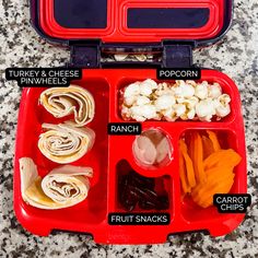 an open red lunch box filled with different types of food and labeled labels on it