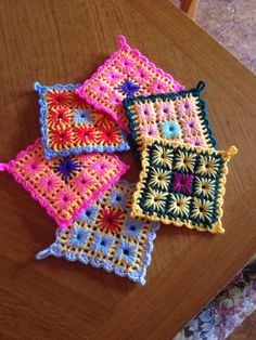 three crocheted squares sitting on top of a wooden table