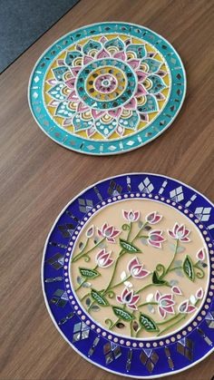 two decorative plates sitting on top of a wooden table