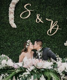 a bride and groom kissing in front of a floral backdrop with the word s & k on it