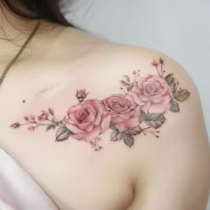 a woman's shoulder with pink roses on it and greenery around the breast