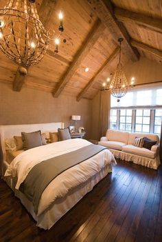 a large bed sitting inside of a bedroom under a chandelier