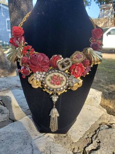 a necklace with red flowers and gold accents on a black mannequin neckline