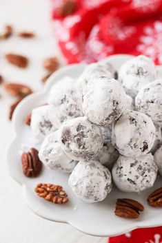 a white plate topped with snowball cookies and pecans