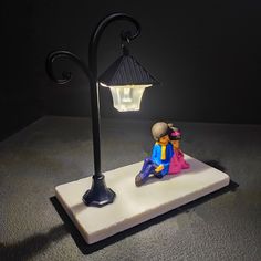 a small figurine sitting on top of a white base next to a lamp