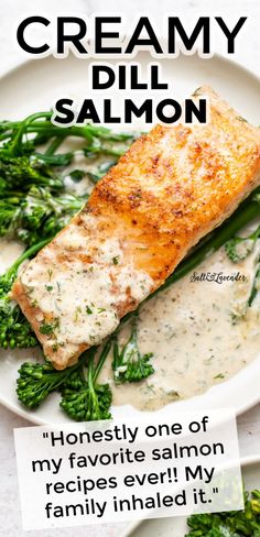 a white plate topped with salmon and broccoli covered in cream dill sauce