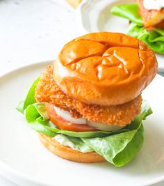 a chicken sandwich with lettuce, tomato and mayonnaise on a white plate