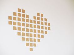 several pieces of brown paper are arranged in the shape of a heart on a white wall