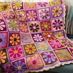 a crocheted granny blanket with flowers on the front and back, sitting on a couch