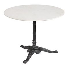 a white marble top table with black metal legs and an ornate design on the base