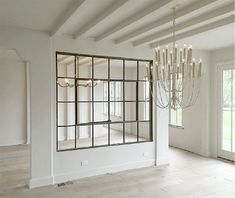 an empty room with a chandelier and large mirror in the center, surrounded by windows