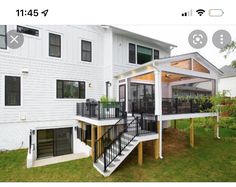 a white house with black railings and glass doors on the front porch is shown