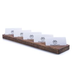 four business cards sitting on top of a wooden holder with white paper attached to it