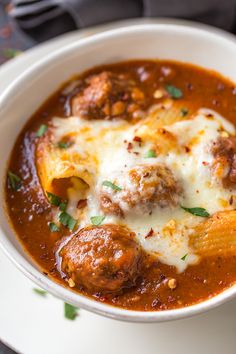 a white bowl filled with meatball soup on top of a table