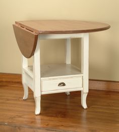 a small table with two drawers on the bottom and one drawer below it, sitting on a hard wood floor