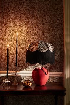 a red apple sitting on top of a wooden table next to a black and white lamp