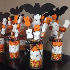 halloween treats in glass jars with bats and pumpkins on the top, sitting on a table