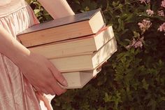 a woman in pink dress holding a stack of books