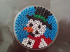 a bunch of different colored beads in a circle on top of a glass table with black and white circles