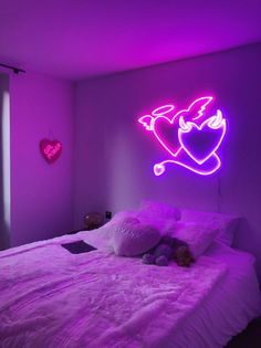 a bed in a room with purple lighting and a heart on the wall above it