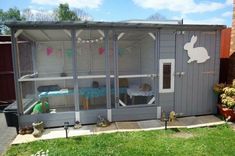 a small gray house with a rabbit in the door and some decorations on the outside