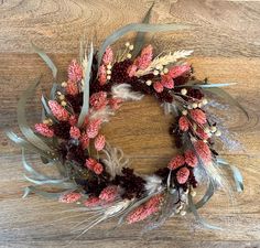 a wreath with feathers and flowers on a wooden surface