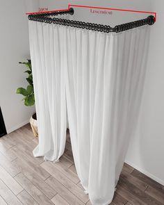 a white curtain with black beading hanging from it's side in front of a potted plant