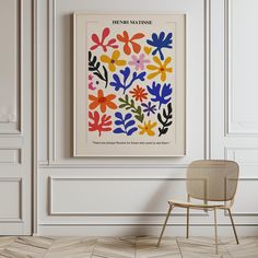 a chair sitting in front of a white wall with a colorful flower pattern on it