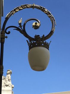 an ornate street light with a blue sky in the backgroung behind it