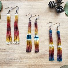 three pairs of multicolored seed beaded earrings on top of a wooden table