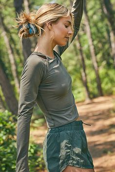 a woman holding a frisbee in her hand while standing on a dirt road