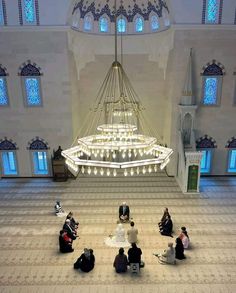 several people sitting on the floor in a large room with chandelier and stained glass windows