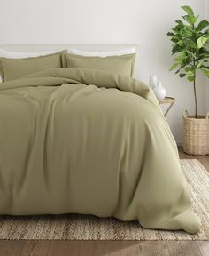 a bed with brown sheets and pillows in a room next to a potted plant