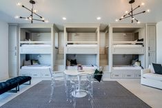 a room with bunk beds, chairs and a table in the middle is lit by lights