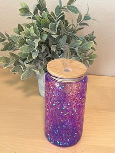 a potted plant sitting on top of a wooden table next to a purple jar