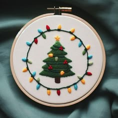 a small christmas tree with lights in a circle on a white wall hanging from a hoop