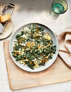 a white plate topped with spinach and cheese next to a glass of green liquid