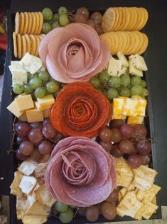 an assortment of cheese, crackers, grapes and flowers