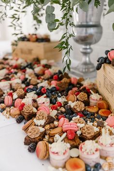 a table topped with lots of desserts next to a vase filled with greenery