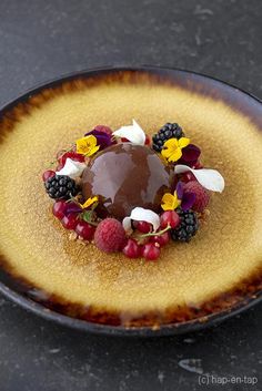 a chocolate dessert with berries, raspberries and blackberries on a yellow plate