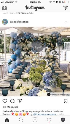 the table is set with blue and white balloons, flowers, and greenery on it