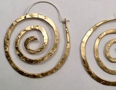 "These swirl hoops are hand pound, shaped and polished. Great for every day. The texture and hand forged quality catches the light and give these simple earrings dimension. Available in solid copper, bronze or sterling silver with hand made ear wires of sterling silver. Large 2 1/8\" H x 1 7/8\" W Ancient spiral meaning: Evolution, Life, Consciousness, Creation Finish: Satin finish is a matte brushed finish. High shine is a brilliant high polish. Each pair is individually shaped, pound and match Hammered Brass Spiral Jewelry, Unique Hammered Spiral Jewelry, Spiral Brass Jewelry, Handmade Spiral Wrap Earrings, Handmade Unique Spiral Wrap Earrings, Unique Handmade Spiral Wrap Earrings, Handmade Spiral Metal Hoop Earrings, Unique Hand Forged Spiral Jewelry, Electroformed Spiral Metal Jewelry