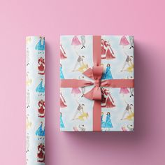 a present wrapped in wrapping paper next to a pink background with princesses on it