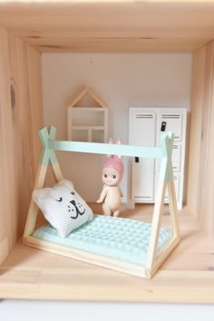 a doll house with a computer keyboard, pillow and stuffed animal on the shelf next to it