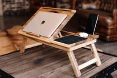 an apple laptop sitting on a wooden table with a tablet in it's holder