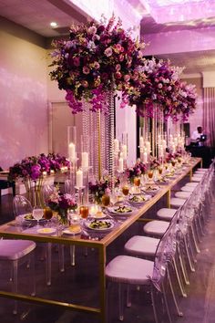 a long table with purple flowers and candles is set up for a formal dinner or party