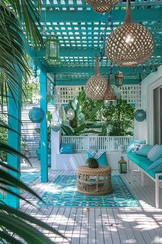 an outdoor covered porch with blue cushions and wicker lamps hanging from the pergolated roof