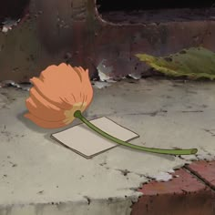 an orange flower sitting on top of a piece of paper next to a brick wall