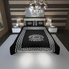 a bed with a black and white comforter in a bedroom next to a chandelier