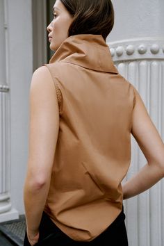 Make a statement with the Marcy Sleeveless Top, a structured and sleek shirt that transforms into a turtleneck. Marcy's unique turtleneck can be worn in two ways — fold in half to wear it gathered at the neckline, or amp up the oversize by standing up the collar for free-form volume. Crafted from 100% European poplin cotton, Marcy provides effortless day-to-night styling possibilities. [SPLIT] Yada, in chestnut, is 5'9" (175 cm) tall, wearing size XS. Sam, in light beige, is 5'8" (173 cm) tall, Chic Cotton Turtleneck Top, Chic High Neck Cotton Tops, Versatile Cotton Turtleneck Top, Summer Mock Neck Turtleneck Top For Layering, Chic High Neck Tank Top For Fall, Chic Cowl Neck Top, Chic Sleeveless Mock Neck Top For Work, Brown High Neck Top For Layering, Fall Workwear Cowl Neck Top